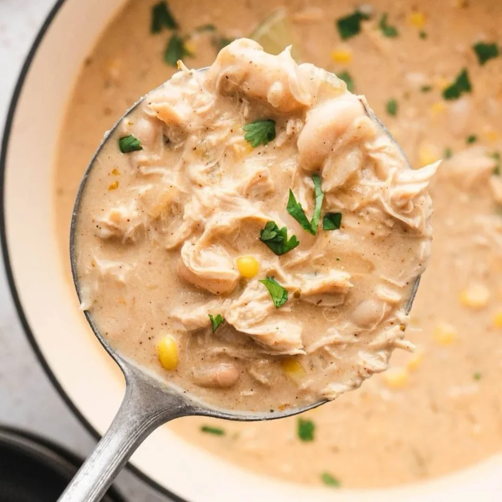 White Chicken Chili Recipe: Creamy, Ready in 40 Minutes 2 Creamy white chicken chili with shredded chicken, white beans, corn, and fresh cilantro in a ladle.
